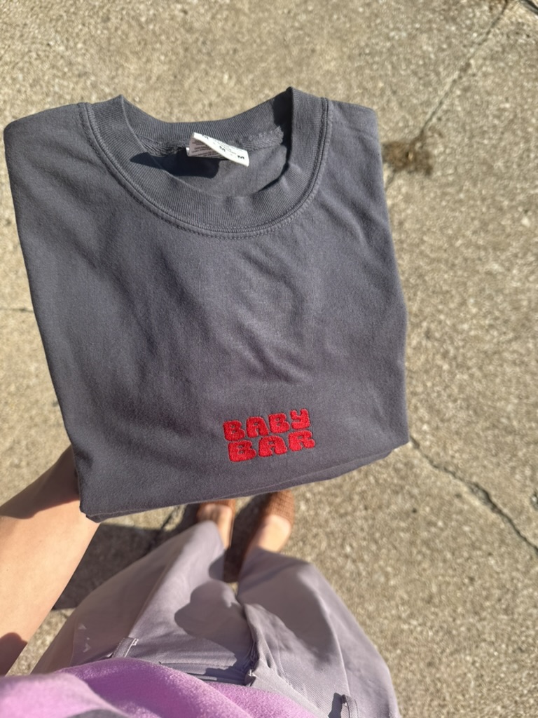 Folded charcoal BABYBAR bar staff T-shirt with red embroidered lettering